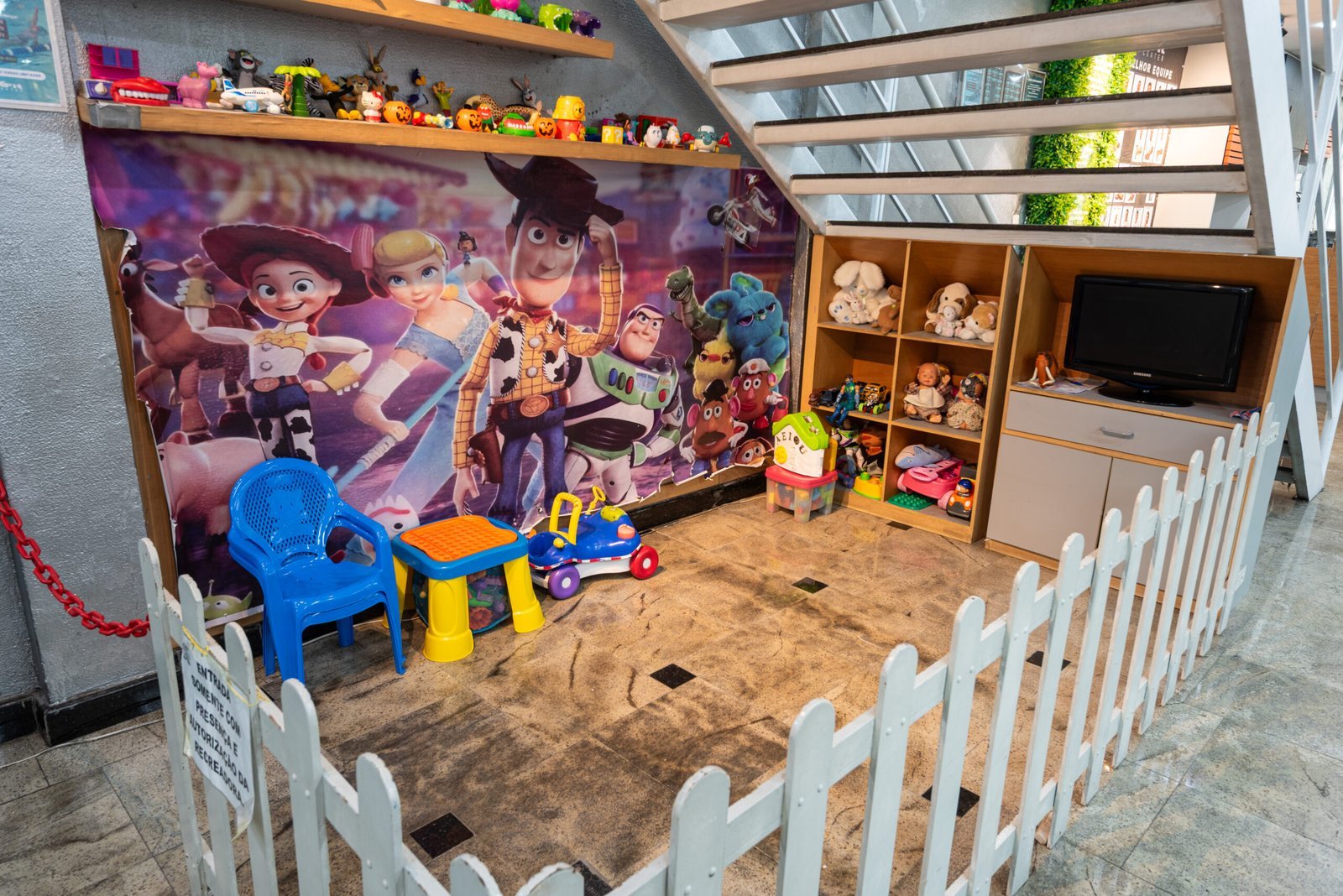Espaço kids da MaxFit com brinquedos, mesa de atividades e área delimitada para as crianças.