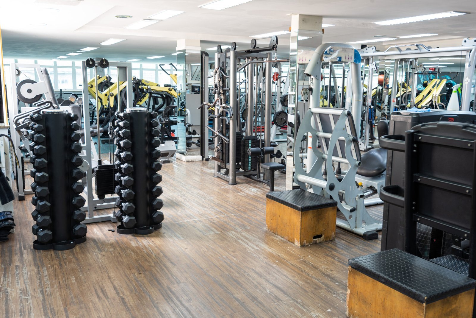 Suportes de halteres e estação de cabos na musculação da MaxFit.